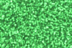 Blurred green decorative sequins. Background image with shiny bokeh lights from small elements photo