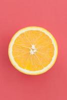 Top view of a one orange fruit slice on bright background in red color. A saturated citrus texture image photo