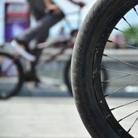 A BMX bike wheel against the backdrop of a blurred street with cycling riders. Extreme Sports Concept photo