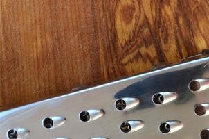 The chrome grater lies on the cutting board with a lot of scars from the ax and knife. Background image for cooking recipes photo