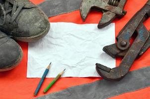 Adjustable wrenches with old boots and a sheet of paper with two pencils photo