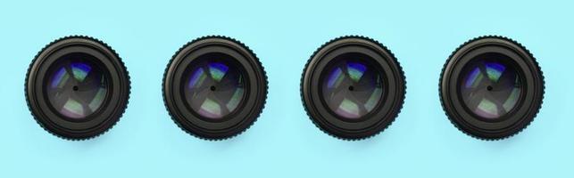 A few camera lenses with a closed aperture lie on texture background of fashion pastel blue color paper photo