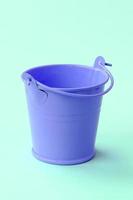 A miniature empty lilac bucket lies on a green pastel background photo