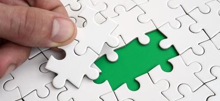 The human hand fills the last missing elements of the surface from the jigsaw puzzle. The concept of the completion of the initiated cases photo