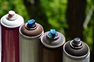 A few used aerosol paint sprayers lie on the windowsill in the workshop of a graffiti artist. The concept of street art and illegal drawing on the walls. Youth hobby photo