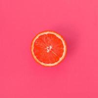 Top view of a one grapefruit slice on bright background in light pink color. A saturated citrus texture image photo