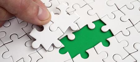 The human hand fills the last missing elements of the surface from the jigsaw puzzle. The concept of the completion of the initiated cases photo