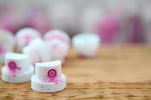 The soiled pink nozzles from the paint sprayer lies on a wooden plank on a background of a many dirty spray cans photo