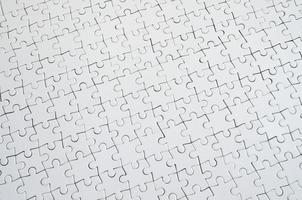 Close up texture of a white jigsaw puzzle in assembled condition. Top view. Many components of a large whole mosaic are united photo