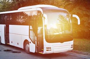 autobús turístico blanco para excursiones. el autobús está estacionado en un estacionamiento cerca del parque foto