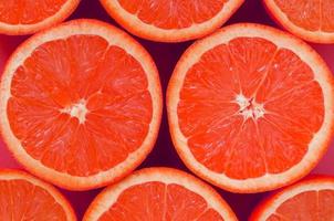 Top view of a several grapefruit slices on bright background in pink color. A saturated citrus texture image photo