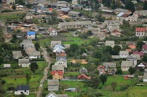 A beautiful view of the village of Mezhgorye, Carpathian region. A lot of residential buildings surrounded by high forest mountains and long river photo