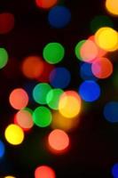 Blurred festive colorful lights over black useful as background. All main colors included. Red, yellow, green and blue photo