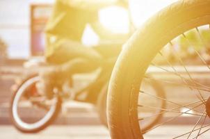 A BMX bike wheel against the backdrop of a blurred street with cycling riders. Extreme Sports Concept photo