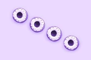 Many small plastic donuts lies on a pastel colorful background. Flat lay minimal pattern. Top view photo