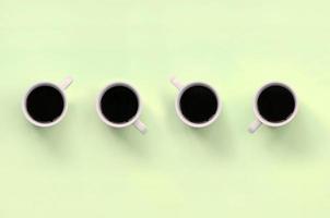 Many small white coffee cups on texture background of fashion pastel lime color paper photo