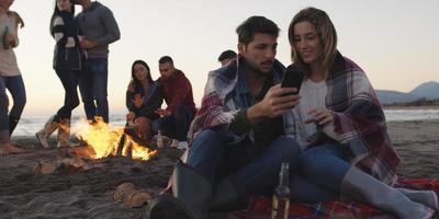 Couple enjoying bonfire with friends on beach photo