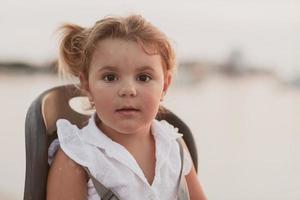 A portrait of a smiling little girl sitting in a bicycle seat. Selective focus photo