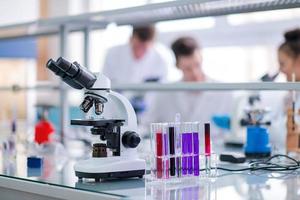 Microscope on the workplace near test tubes photo