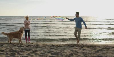 couple with dog having fun on beach on autmun day photo