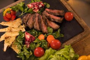 Juicy slices of grilled steak on wooden board photo