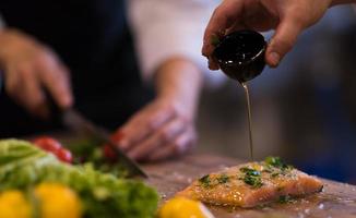 Chef hands preparing marinated Salmon fish photo