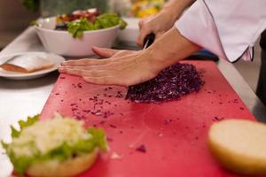 chef cortando ensalada para hamburguesa foto