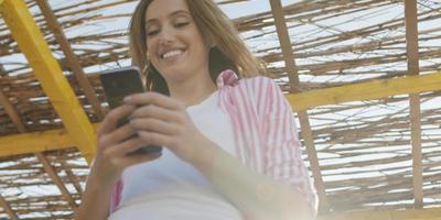 mujer smartphone enviando mensajes de texto por teléfono celular en la playa foto