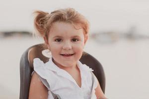 A portrait of a smiling little girl sitting in a bicycle seat. Selective focus photo