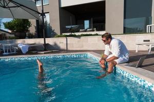 Happy family enjoys vacation in luxury house with pool. Father spends time with son having fun in pool. Selective focus photo