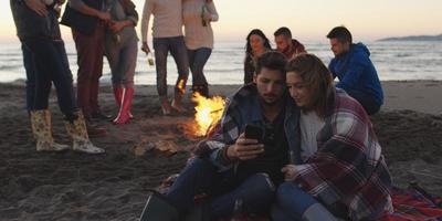 Couple enjoying bonfire with friends on beach photo