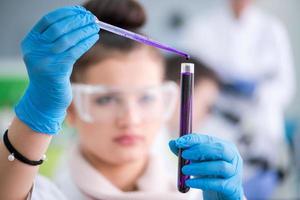 female student with protective glasses making chemistry experiment photo