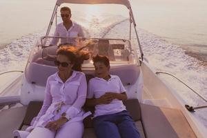 una pareja mayor con ropa informal con su hijo disfruta mientras viaja en un bote en el mar al atardecer. el concepto de una familia feliz. enfoque selectivo foto