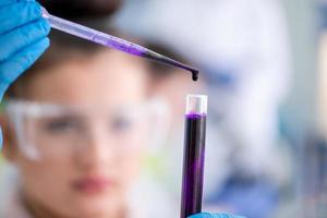 female student with protective glasses making chemistry experiment photo