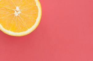 Top view of a one orange fruit slice on bright background in red color. A saturated citrus texture image photo