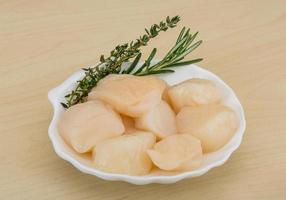 Raw scallops on the plate and wooden background photo