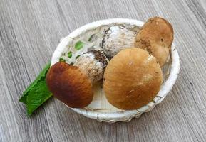 Wild Mushrooms in a basket on wooden background photo