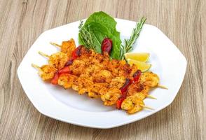 Prawn skewer on the plate and wooden background photo