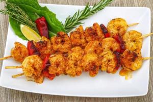 Prawn skewer on the plate and wooden background photo