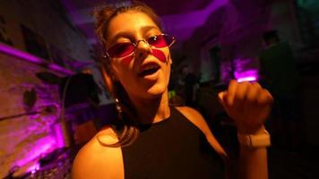 Woman in sunglasses dances in a club party video