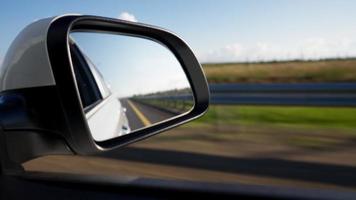 vista de lado espelha o interior de um carro dirigindo ao longo da estrada em um dia ensolarado. conceito de veículos e transporte. ninguém. video