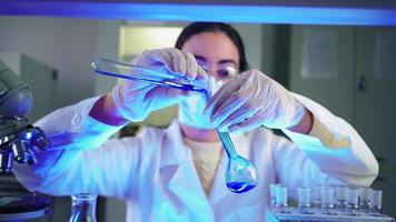 Wissenschaftlerin im Labor, die chemische Experimente mit blauer Flüssigkeit in Reagenzgläsern durchführt. Extraktion von DNA und Molekülen. Impfstoffentwicklung. forschung, biochemie, konzept der pharmazeutischen medizin. video