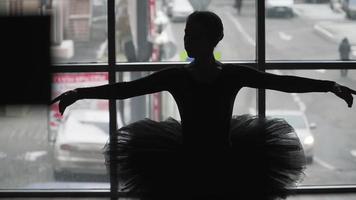 Silhouette einer Ballerina auf dem Hintergrund der Stadt ein wunderschön bewegender Tanz. in einem schwarzen Tutu und Spitzenschuhen. das Bild des schwarzen Schwans aus dem Ballett. Zeitlupe video