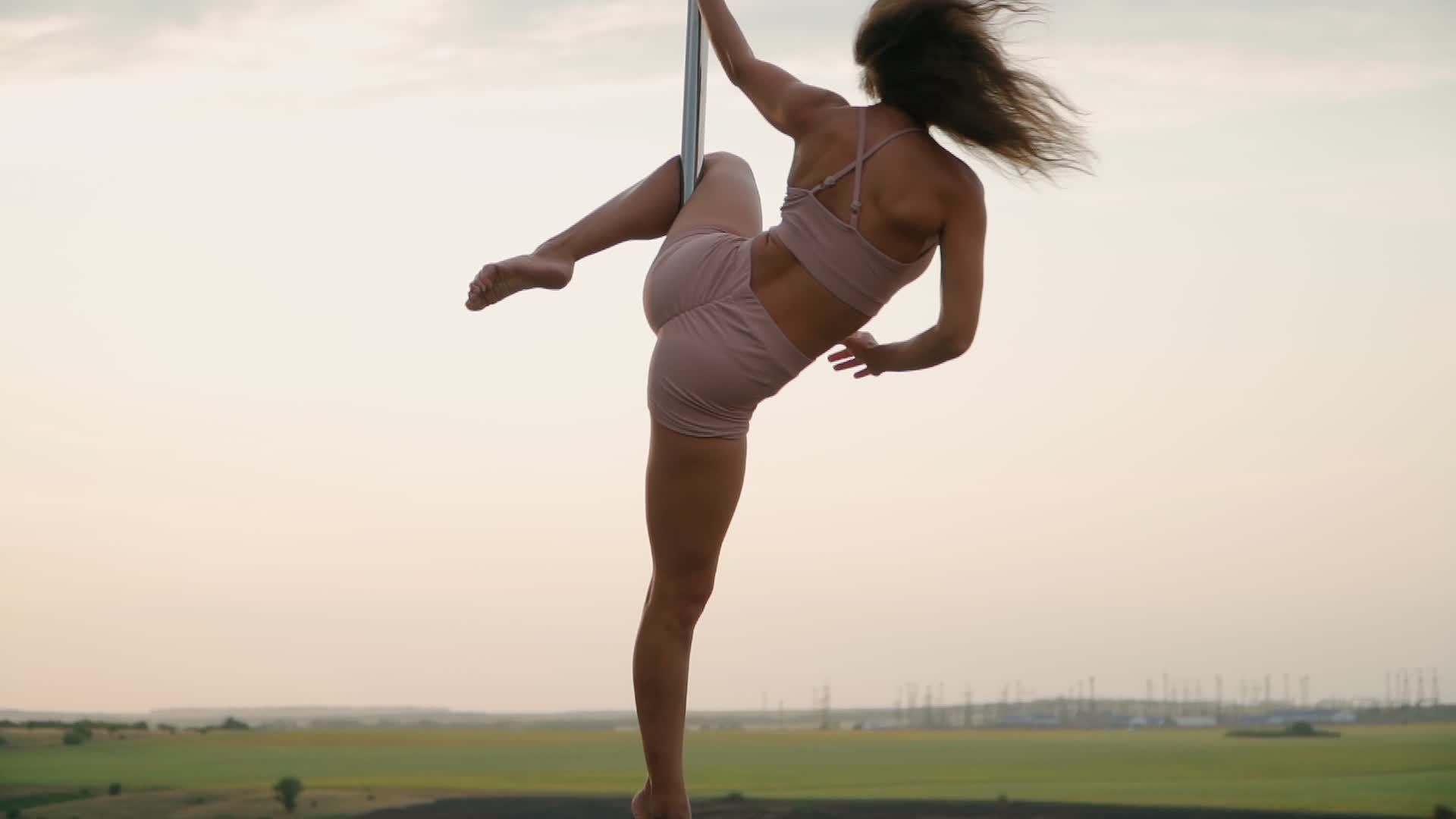 https://static.vecteezy.com/system/resources/thumbnails/012/771/723/original/beautiful-athletic-woman-performs-tricks-on-the-pole-against-the-background-of-sunset-in-the-field-beauty-and-body-care-female-sports-and-fitness-slow-motion-video.jpg