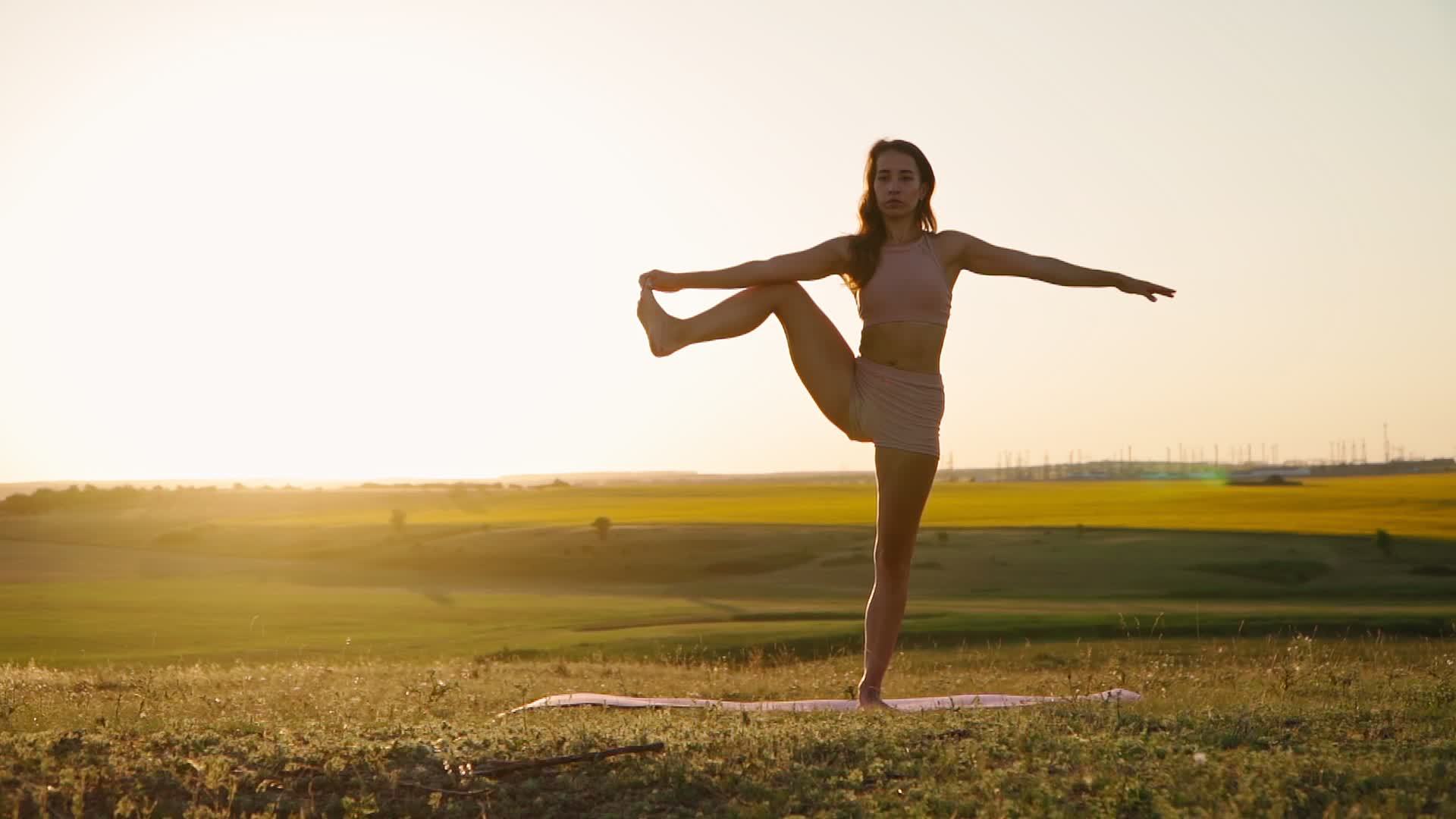 Young woman is practicing yoga outdoors in park evening on