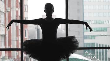 Silhouette of a ballerina on a background of the city a beautifully moving dance. In a black tutu and Pointe shoes. The image of the black Swan from the ballet. Slow motion video