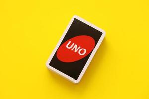 TERNOPIL, UKRAINE - MAY 15, 2022 Many colorful UNO game cards on yellow background. UNO is an American shedding-type card game that is played with a specially printed deck photo