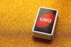 TERNOPIL, UKRAINE - MAY 15, 2022 Many colorful UNO game cards on golden background. UNO is an American shedding-type card game that is played with a specially printed deck photo