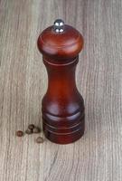 Pepper mill on wooden background photo