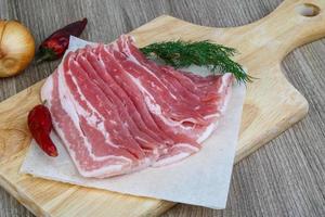 Raw bacon on wood photo